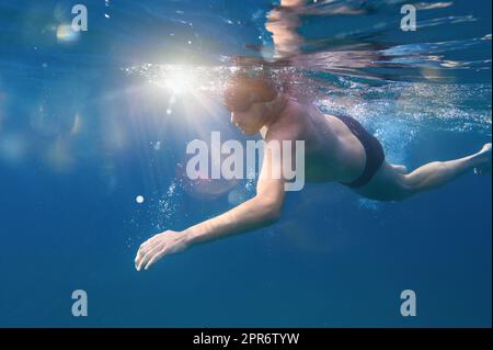 Sportlicher Mann schwimmt schnell im Meer Stockfoto