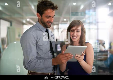 Mit einer digitalen Brainstorming-Sitzung Dinge umsetzen. Aufnahme von zwei Kollegen, die zusammen ein digitales Tablet in einem Büro nutzen. Stockfoto