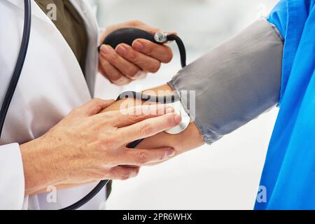 Verantwortungsvolle Maßnahmen zur Erhaltung eines gesunden Herzens ergreifen. Zugeschnittenes Bild eines Arztes, der den Blutdruck eines Patienten überprüft. Stockfoto