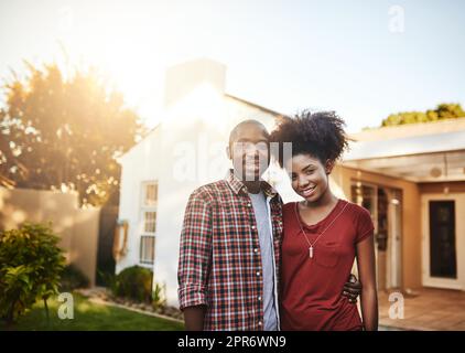 Stolze Hausbesitzer zum ersten Mal. Porträt eines jungen Paares, das vor dem neuen Haus steht. Stockfoto