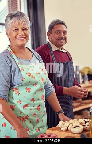 Es ist besser, wenn wir zusammen kochen. Aufnahme eines reifen Paares, das zu Hause zusammen kocht. Stockfoto