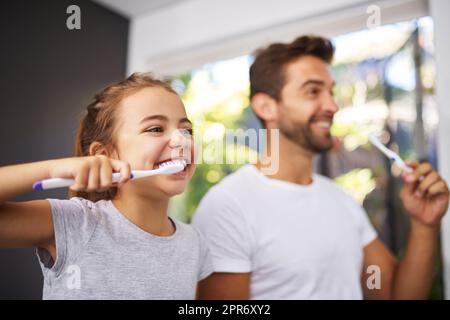 Nein, Papa, Pinsel so. Eine kleine Aufnahme eines hübschen Vaters und seiner Tochter, die sich im Badezimmer die Zähne putzten. Stockfoto