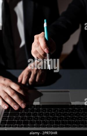 Ein Mann Tippt Auf Dem Laptop Und Eine Frau Zeigt Mit Dem Stift Auf Eine Wichtige Nachricht. Ein Geschäftsmann, Der Über Computer Schreibt, Und Eine Geschäftsfrau, Die Grausame Informationen Präsentiert. Stockfoto