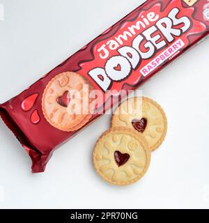 Ein Päckchen Jammie Dodgers Kekse, hergestellt von Burtons Biscuit Company. die packung wird geöffnet und zwei Kekse werden von oben auf weißem Hintergrund nach vorne gelegt Stockfoto