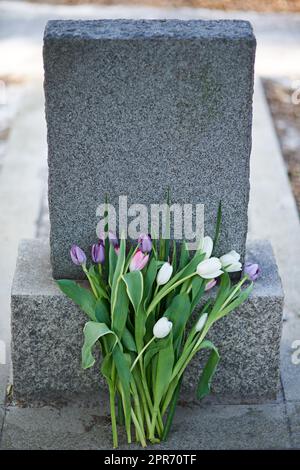 Blumen für die teuer abgereisten. Aufnahme eines Grabsteins auf einem Friedhof. Stockfoto