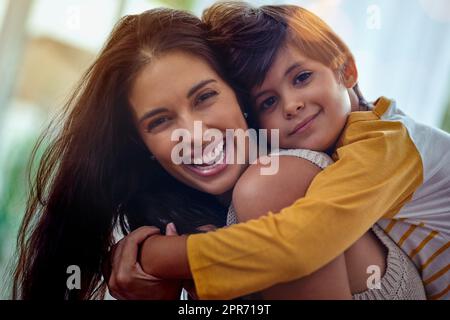 Mama, die beste Freundin, die ein Junge je haben könnte. Aufnahme eines entzückenden kleinen Jungen, der seine Mutter zu Hause liebevoll umarmt. Stockfoto