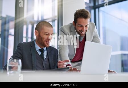 Sich zusammenfinden, um es zu erledigen. Aufnahme von zwei Geschäftsleuten, die in einem modernen Büro zusammen einen Laptop benutzen. Stockfoto