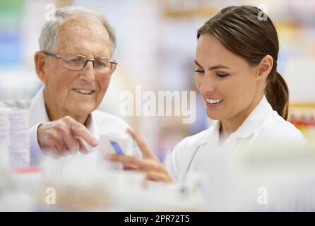 Sicherstellen, dass Kunden das finden, was sie benötigen. Aufnahme eines jungen Apothekers, der einem älteren Kunden hilft. Stockfoto