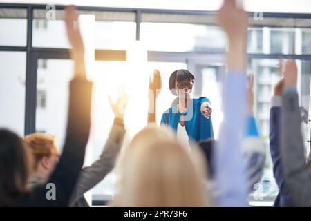 Erfolgreiche Seminare. Ausgeschnittene Aufnahme einer Gruppe von Menschen, die in einer Klasse die Hände heben. Stockfoto