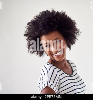 Es gibt eine Menge zu lächeln. Studioportrait einer attraktiven und glücklichen jungen Frau, die vor grauem Hintergrund posiert. Stockfoto