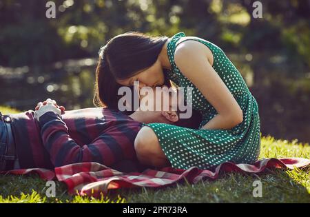 Nichts sagt Romantik wie ein Picknick im Park. Aufnahme eines liebevollen jungen Paares, das sich auf einer Picknickdecke im Park entspannt. Stockfoto