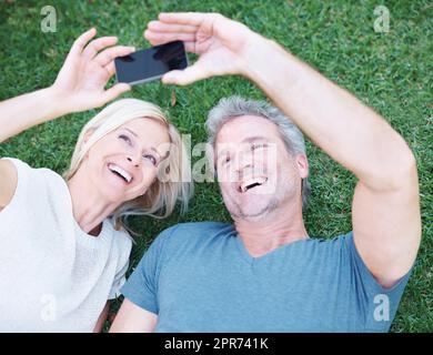 Dies ist eines für das Album. Ein glückliches reifes Paar, das mit einem Smartphone ein Bild von sich macht. Stockfoto