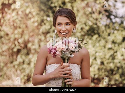 Shes begeistert über ihre Hochzeit. Ausgeschnittene Aufnahme einer schönen jungen Braut, die lächelt, während sie an ihrem Hochzeitstag mit einem Blumenstrauß in den Händen steht. Stockfoto