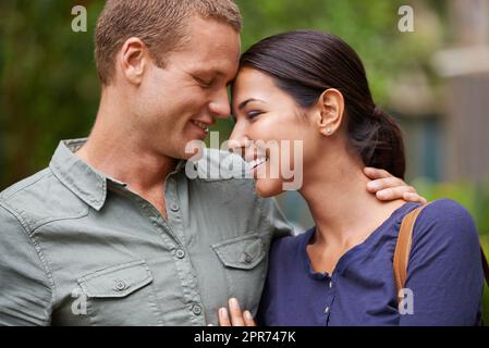 Verloren im Dunst der Romantik im Frühling. Beschnittene Ansicht eines glücklichen jungen Paares, das zusammen im Park steht. Stockfoto