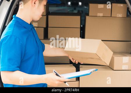 Der man-Kurier in Uniform hält Dokumente in der Zwischenablage, Checkliste Paketpostkartons Stockfoto