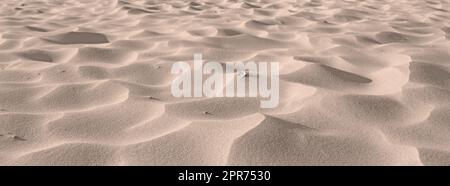 Strandsand aus Wüstendünen entlang der Küste in der Natur mit viel Platz an einem sonnigen Tag. Nahaufnahme einer landschaftlich reizvollen Außenlandschaft mit rauer und welliger Oberflächenstruktur. Ein ruhiger Ort, um sich zu entspannen Stockfoto