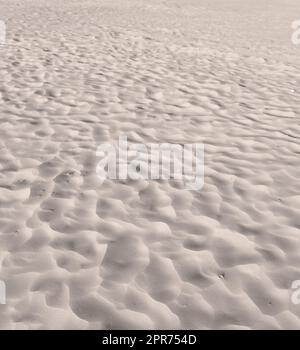 Strandsand aus Wüstendünen mit Wellen entlang der Küste in der Natur an einem sonnigen Tag. Nahaufnahme einer landschaftlich reizvollen Landschaft an der Küste mit Hintergrundinformationen im Freien. Ein ruhiger Ort, um sich wie ein Zen zu fühlen Stockfoto