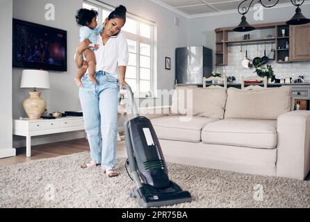 Ihr Geist ist geschickt an verschiedenen Orten. Aufnahme einer jungen Mutter, die ein Mobiltelefon benutzte, während sie die Hausarbeit abschloss und ihr Baby zu Hause hielt. Stockfoto