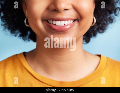 Lächelnd, während ich noch Zähne habe. Ausgeschnittene Aufnahme einer nicht erkennbaren Frau, die allein vor blauem Hintergrund im Studio steht. Stockfoto