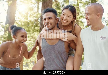 Warum meine Beine benutzen, wenn ich meine Freunde benutzen kann. Aufnahme einer vielfältigen Gruppe von Freunden, die sich beim Campen im Wald verbinden. Stockfoto