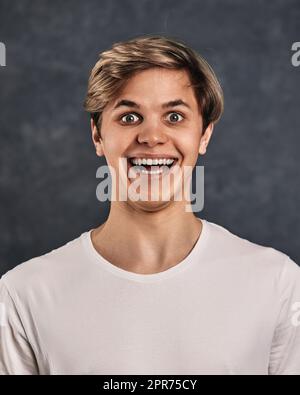 Lustige junge gut aussehende Kerl auf grauem Hintergrund. Stockfoto