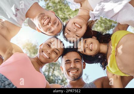 Leben nach unseren eigenen Bedingungen. Low-Angle-Aufnahme einer vielfältigen Gruppe von Freunden, die während eines Tages im Wald zusammengekauert stehen. Stockfoto