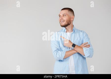Junger, hübscher bärtiger Mann, der zur Seite zeigt Stockfoto