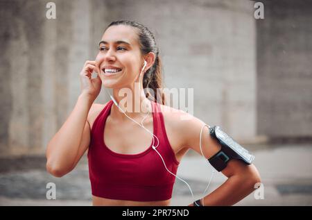 Musik, die dich bewegt. Kurze Aufnahme einer attraktiven jungen Sportlerin, die beim Laufen im Freien Musik hört. Stockfoto