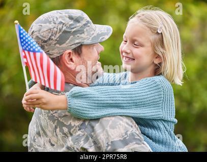 Alle Familien sind unterschiedlich und einzigartig. Aufnahme eines Vaters, der aus der Armee zurückkehrt und seine Tochter draußen umarmt. Stockfoto