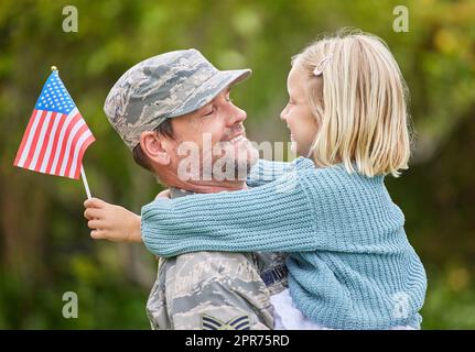 Familien sollten jedes Mitglied einzigartige Identität feiern. Aufnahme eines Vaters, der aus der Armee zurückkehrt und seine Tochter draußen umarmt. Stockfoto