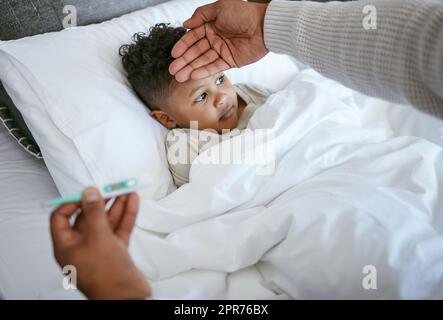 Ich mag es nicht, wenn mein Baby krank ist. Ein kurzer Schuss einer Frau, die die Temperatur ihres Sohnes überprüft. Stockfoto
