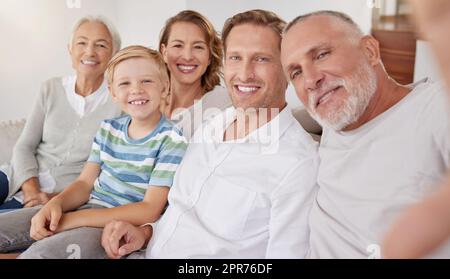 Porträt einer glücklichen, weißhäutigen Familie, die zu Hause Selfies macht. Der kleine Junge entspannt sich und verbindet sich mit sorglosen Eltern und Großeltern, während er Fotos und Bilder für besondere Erinnerungen aufnimmt Stockfoto