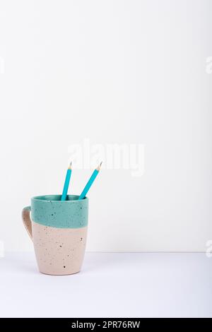 Tasse Mit Zwei Bleistiften Innen Auf Dem Schreibtisch Platziert. Becher Mit Stifte Auf Dem Tisch. Fall Mit Darin Eingeschritzener Schrift. Gehäuse Mit Büromaterial. Stockfoto