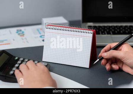 Geschäftsfrau Mit Stift Und Zeigen Auf Dem Schreibtisch Mit Notizbuch Mit Neuen Ideen. Frau Im Anzug Hat Einen Bleistift Auf Dem Tisch Mit Notizblock Und Späten Updates. Stockfoto