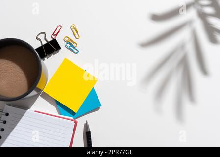 Wichtige Informationen Am Schreibtisch Mit Stift, Notizbuch, Büroklammern, Kaffee Und Notizen. Auf Dem Tisch Wird Eine Nachricht Mit Clips, Becher, Bleistift Und Memos Angezeigt. Stockfoto