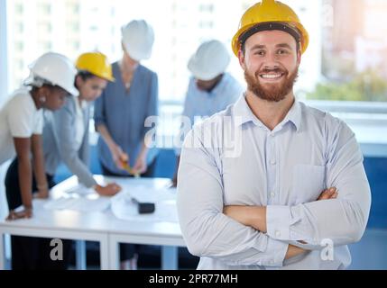 Haben Arbeit geleistet. Aufnahme eines jungen Geschäftsmannes, der bei der Arbeit mit gekreuzten Armen in einem Büro steht. Stockfoto