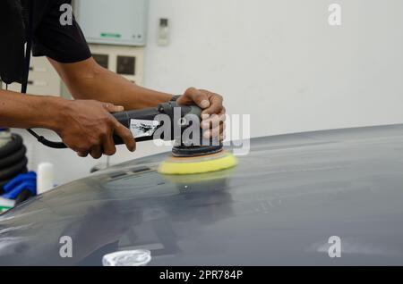 Mann hält Werkzeug polieren Mechaniker Auto Reparatur detailliert Haube Auto Kratzer Wartung in Garage Autowäsche Job. Stockfoto