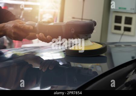 Mann hält Werkzeug polieren Mechaniker Auto Reparatur detailliert Haube Auto Kratzer Wartung in Garage Autowäsche Job. Stockfoto