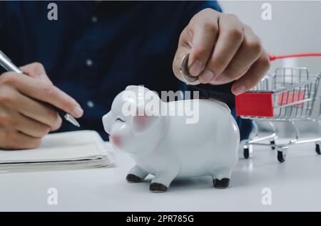 Business man Hand hält Münze Geld sparen bei Sparschwein.Business Economy Management Finanzierung Investmentmarkt und Shopping-Konzept. Stockfoto