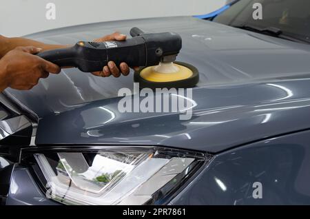 Mann hält Werkzeug polieren Mechaniker Auto Reparatur detailliert Haube Auto Kratzer Wartung in Garage Autowäsche Job. Stockfoto