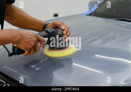 Mann hält Werkzeug polieren Mechaniker Auto Reparatur detailliert Haube Auto Kratzer Wartung in Garage Autowäsche Job. Stockfoto