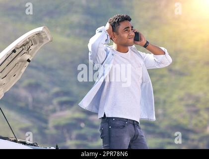 Wann könnt ihr hierher kommen? Ausgeschnittene Aufnahme eines hübschen jungen Mannes am Telefon mit Pannenhilfe nach einem Fahrzeugausfall. Stockfoto