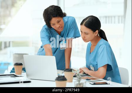 Lassen Sie uns ein wenig recherchieren. Aufnahme von zwei jungen Ärztinnen, die in einem Krankenhaus einen Laptop benutzen. Stockfoto