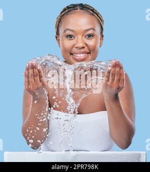 So starte ich in den Morgen. Studioporträt einer attraktiven jungen Frau, die ihr Gesicht vor blauem Hintergrund wäscht. Stockfoto