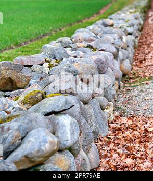 Nahaufnahme einer Steinmauer aus Felsbrocken und Steinen draußen. Hintergrund von rustikalem, ländlichem Gebäude und Mauerwerk. Historisches Wohnungsdesign oder antike Architektur eines alten Bauwerks im Freien Stockfoto