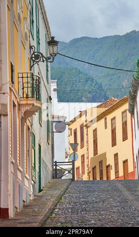 Enge Straße oder Gasse zwischen bunten Gebäuden in Santa Cruz, de La Palma. Helle und lebendige klassische Architektur in einer kleinen Stadt oder einem Dorf. Wunderschöne Häuser oder Häuser im Vintage-Design Stockfoto