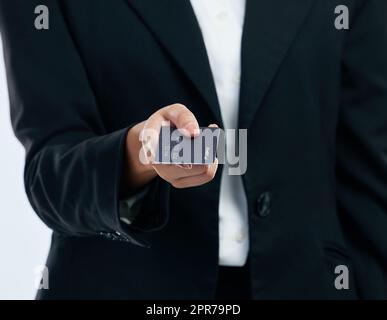 Geld ist ein schrecklicher Meister, aber ein ausgezeichneter Diener. Eine unkenntliche Geschäftsfrau, die eine Kreditkarte vor einem grauen Hintergrund hält. Stockfoto