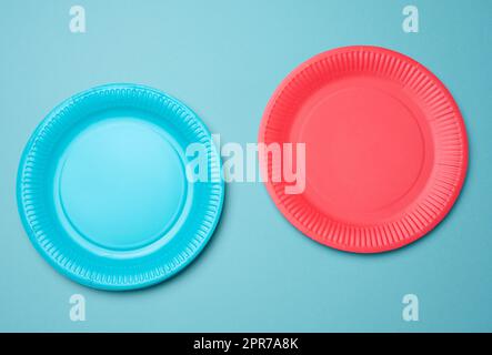 Leere blaue, rote Papiereinwegplatten auf blauem Hintergrund, Draufsicht Stockfoto