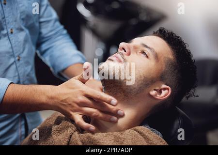 Er reinigt gut. Ein hübscher junger Mann, der von einem Friseur gepflegt wird. Stockfoto