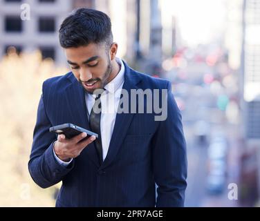 Erfolg kommt in der Regel zu denen, die zu beschäftigt sind, um nach ihm zu suchen. Ein junger Geschäftsmann mit seinem Handy draußen. Stockfoto